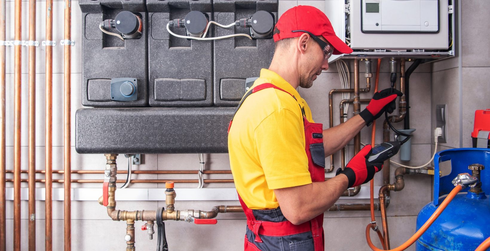 Engineer using a handheld gas analyser to test pipework beside a commercial boiler